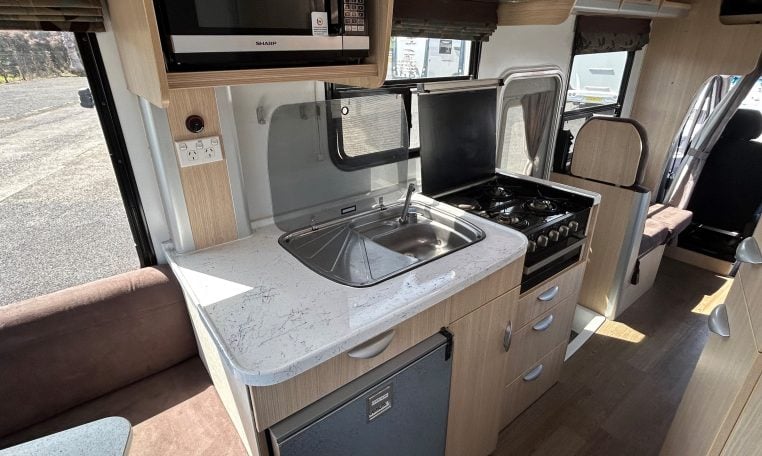 2015 Kea Horizon M721 interior view showing the central kitchen with microwave and stove.