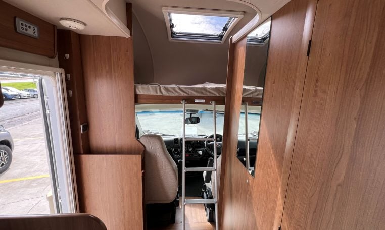 2017 Auto-Trail Tribute 625 motorhome interior showing ladder leading to over-cab bed, compact RV sleeping area with easy access