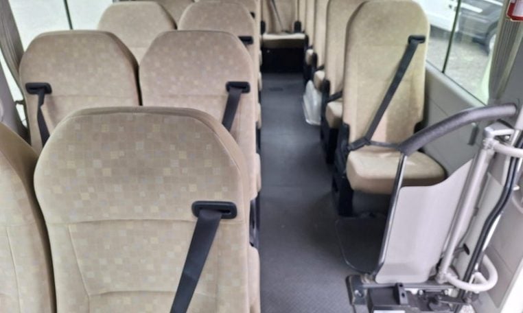 Passenger seats inside a Toyota Coaster bus arranged in rows along the aisle.