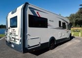2018 Roller Team Pegaso 745 exterior showing the rear driver's side and bike rack next to a lakeside.