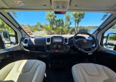Cab and dashboard of the Auto-Trail Frontier Comanche motorhome showing driver and passenger seats with controls and steering wheel.