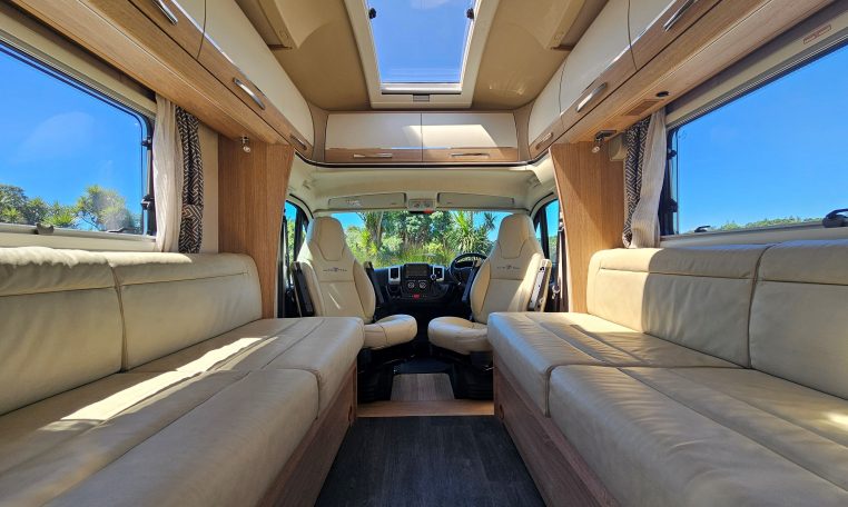Bright Auto-Trail Frontier Comanche motorhome front lounge area with comfortable seating, swivel cab seats, and large windows.