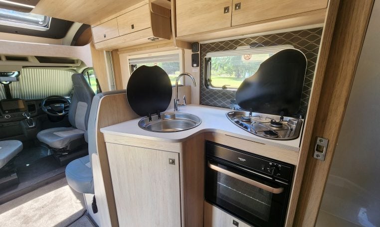Pre-owned 2022 Auto-Trail F-Line F74 4-berth motorhome, interior view of the kitchen with the stove and oven.