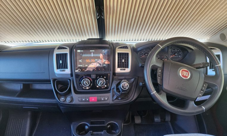 Cab and dashboard of the 2022 Auto-Trail Tracker RL motorhome showing driver and passenger seats with controls and steering wheel.