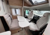 Front lounge dining area in a 2025 Pilote 650GJ motorhome with seating and table extension.