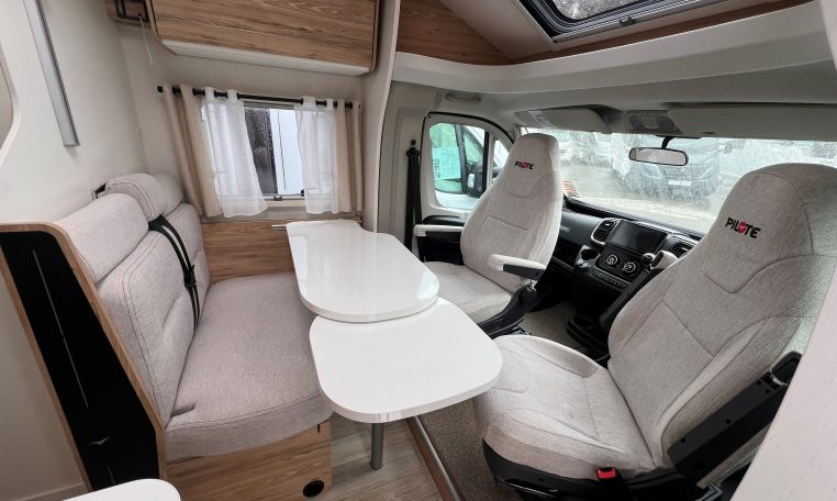 Front lounge dining area in a 2025 Pilote 650GJ motorhome with seating and table extension.