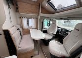 Front lounge dining area in a 2025 Pilote 650GJ motorhome with seating and table.