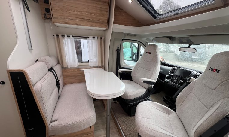 Front lounge dining area in a 2025 Pilote 650GJ motorhome with seating and table.