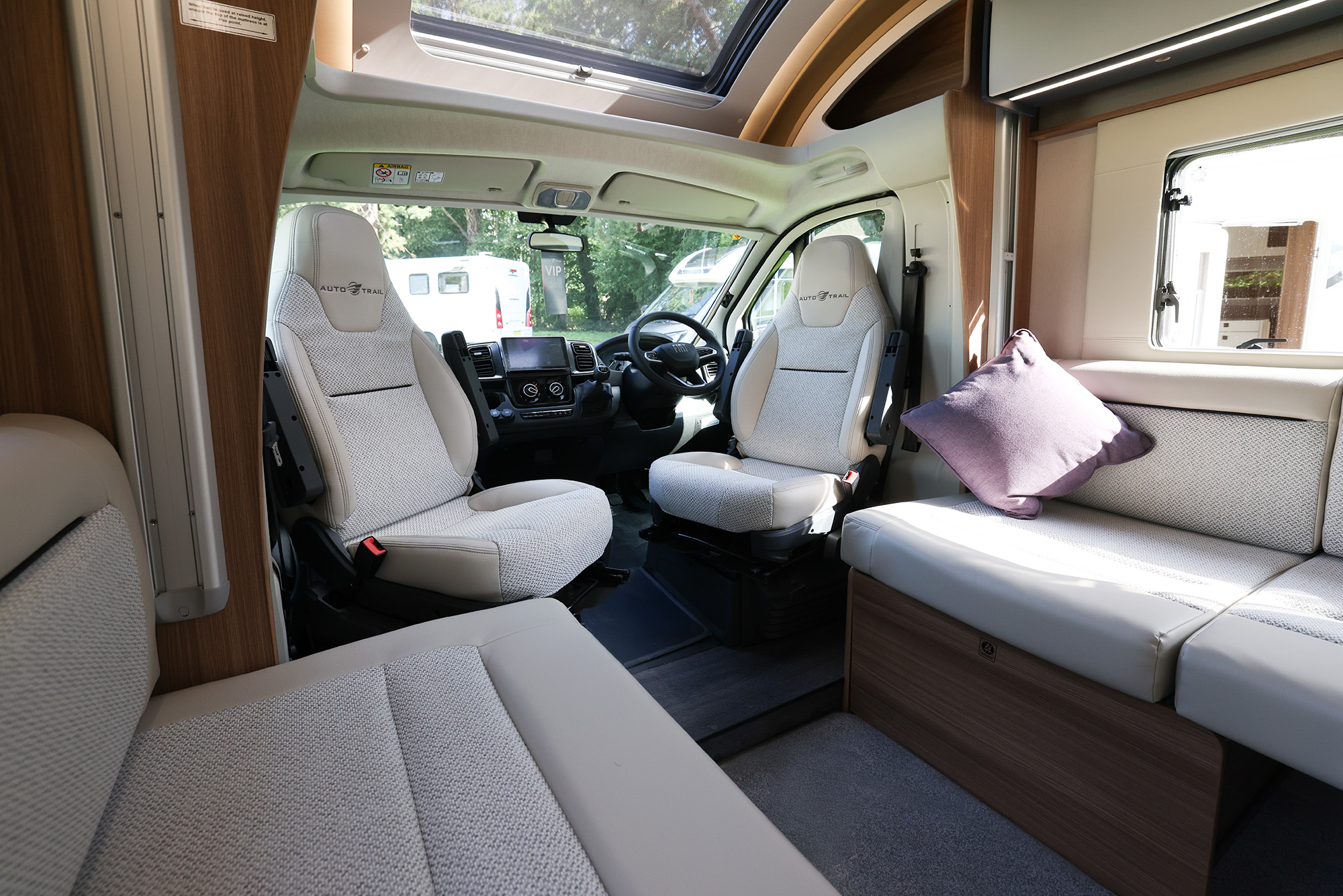 Bright 2026 Auto-Trail Imala 736 motorhome lounge and dining area with comfortable seating, swivel cab seats, and large windows.